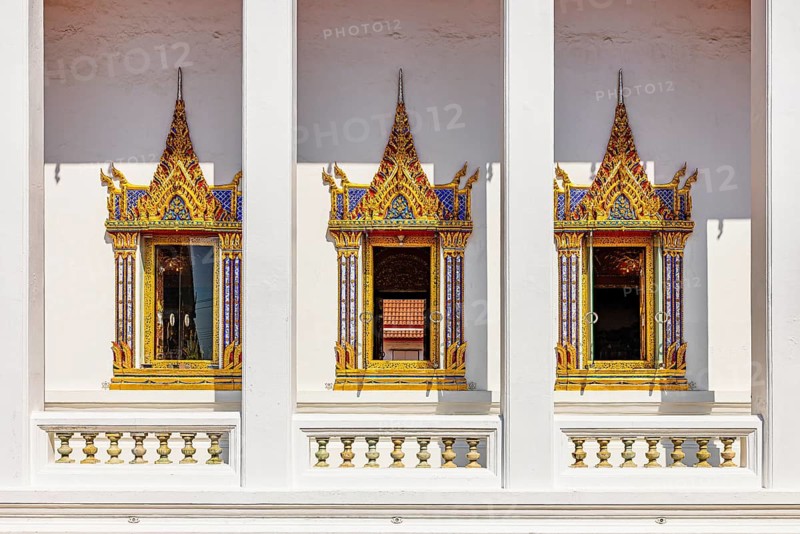 Traditionally decorated temple windows with golden ornaments in symmetrical architecture of a Buddhist temple, Koh Kret river island, Bangkok, Thailand