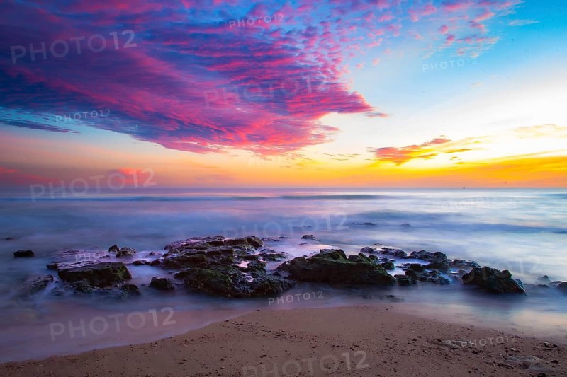 Vivid sunrise over calm coast with colorful sky and rocks in the foreground, sunset, Praia do Amado, Carrapateira, Algarve, west coast, Atlantic, Portugal