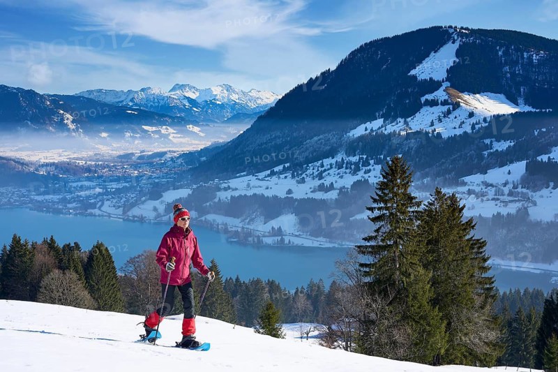 Sportive senior woman hiking with snow shoes in the snowy Allgaeu Alps above Lake Alosee, Immenstadt, Bavria, Germany