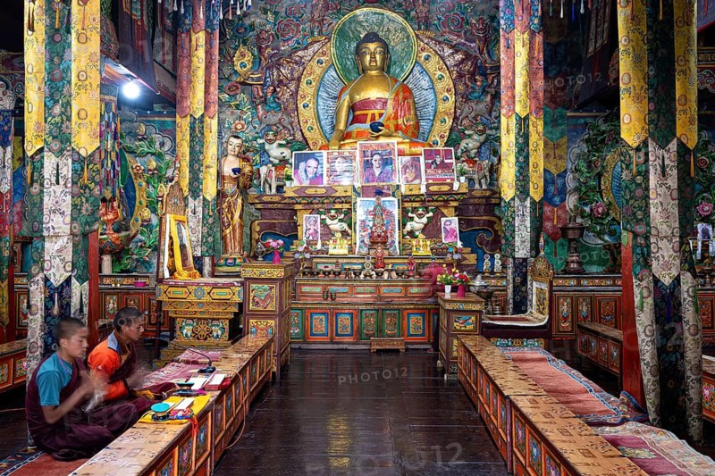 Buddhist prayer room with gilded Buddha statue, two young monks, novices recite holy mantras, Himalayas, Humla region. West Nepal, Nepal
