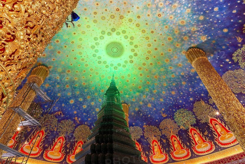 In the emerald green silence of Wat Paknam Phasi Charoen, the glass chedi rises like a glowing heart of light. Golden pillars support a cosmic ceiling that plunges the room into a sense of infinity. The wall paintings tell of Buddha's path to enlightenment and combine earthly beauty with spiritual depth that makes this place so unique, Phasi Charoen district, Thonburi, Bangkok, Thailand