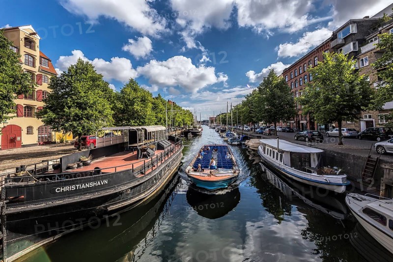 Stadtkanal mit Booten und umgebender Architektur unter einem blauen Himmel, Kopenhagen, Dänemark