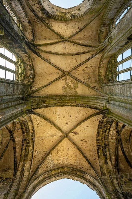 Looking up into the stone cross-rib vault of a Gothic church ruin looking at the sky through the window openings in Pointe Saint-Mathieu, Plougonvelin, Finistère, Brittany, France