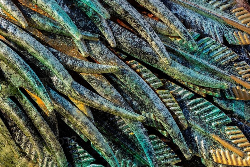Close-up of golden, greenish and turquoise painted carved metal feather details on ornamental waterbird sculpture, Quebec, Canada