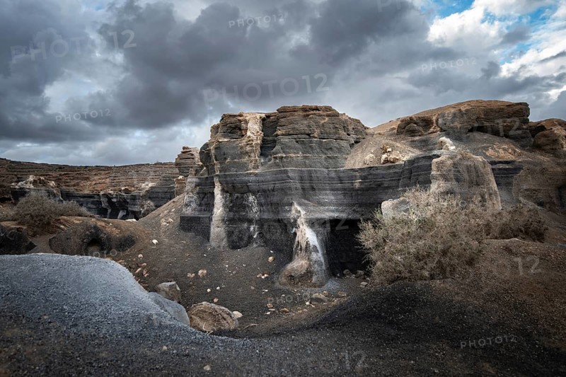 Eroded rock formations, volcanic landscape with dramatic cloudy skies, Ciudad Estratificada or Los Roferos, Antigua Rofera de Teseguite, Lanzarote, Canary Islands, Spain