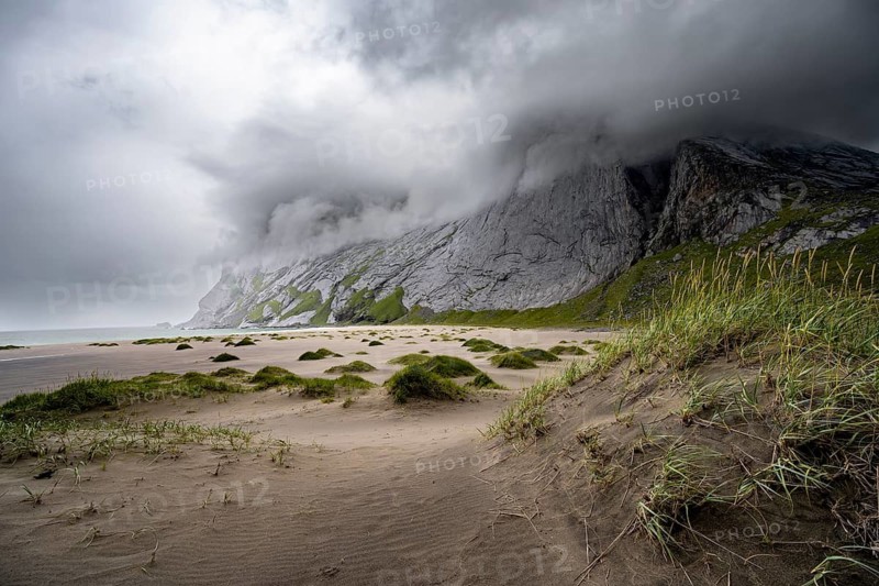 Sand dunes on sandy beaches Bunesstranden between rocky mountain peaks and dramatic clouds, Lofoten, Norway