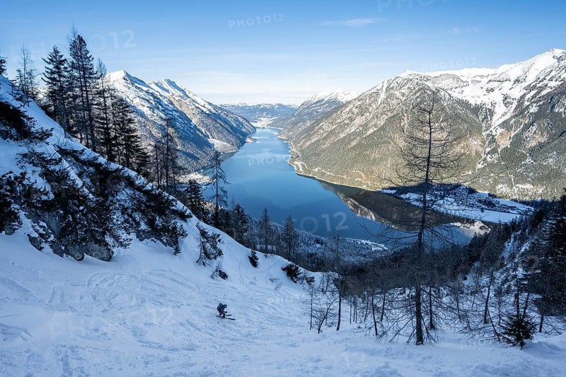 Picturesque view of Achensee and wintry mountain scenery, ski tourers descending from the summit of Bärenkopf, Achensee, Tyrol, Austria