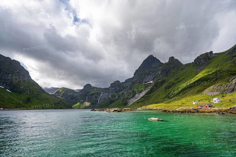 Waterfall and fjord landscape with mountains, Reinefjord, Lofoten, Norway