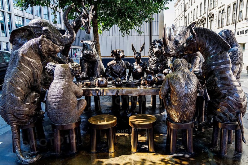 Bronze figures of endangered animals including an elephant, giraffe, rhinoceros and lion gather round a banquet table in the Wild Table of Love, a public sculpture by artists Gillie and Marc installed at Eastbourne Terrace near Paddington station, London, England, United Kingdom