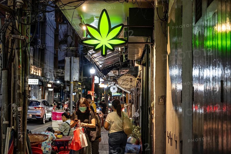 Bangkok, Thailand. August 14th 2026. Green illuminated cannabis leaf sign outside a legal weed shop in the busy downtown district of the Thai capital Bangkok