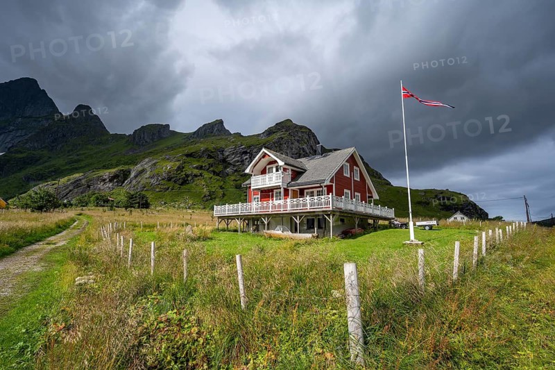 Red wooden house in green landscape, Vindstad, Reinefjord, Lofoten, Norway