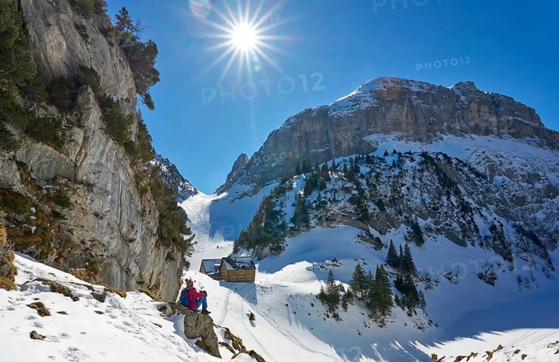 Woman hiking in the snowy mountain landscape of the Alpstein Säntis mountain range, Brülisau, Kanton Appenzell, Switzerland