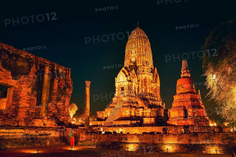 Visitor taking picture Wat Ratchaburana ancient temple in Ayutthaya. Illuminated central prang ruins. Purple twilight blue hour sky. Siam kingdom preserved ancient ruins. Unesco world heritage site