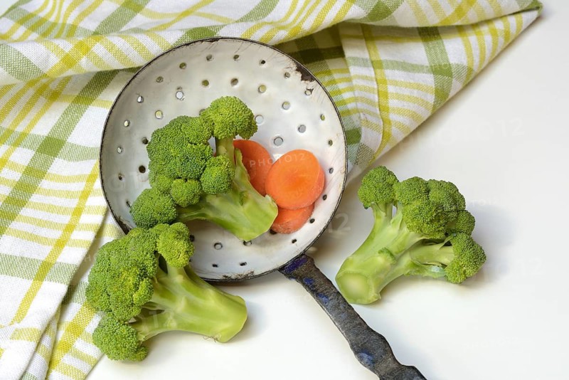 Broccoli in sieve trowel and carrot slices, Brassica oleracea var. italica
