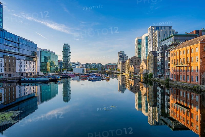 Urban canal with a mix of modern and historic buildings reflecting in water under clear skies, Dublin, Ireland