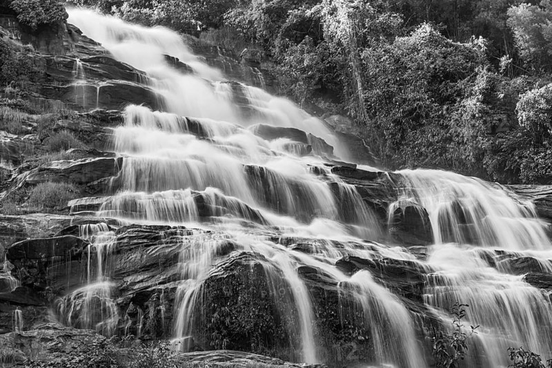 Mae Ya waterfall with cascading flowing water framed by lush tropical vegetation, black and white photo, near Doi Inthanon National Park, Chiang Mai Province, Thailand