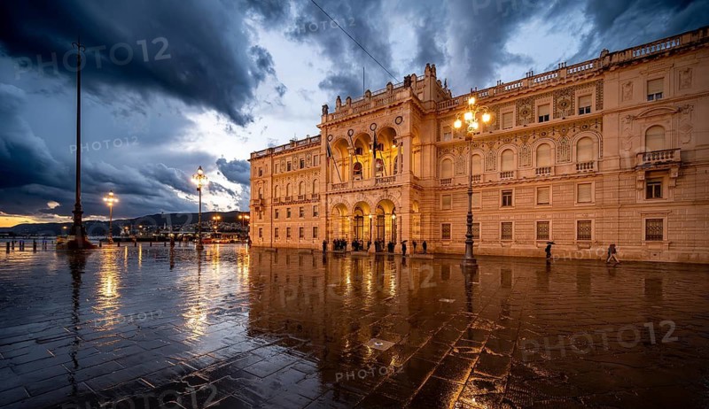 Illuminated square Piazza Unità d'Italia, Palazzo della Luogotenenza Austriaca or Palazzo Governo, with reflection, dramatic clouds, blue hour, old town, Trieste, Friuli-Venezia Giulia region, Italy