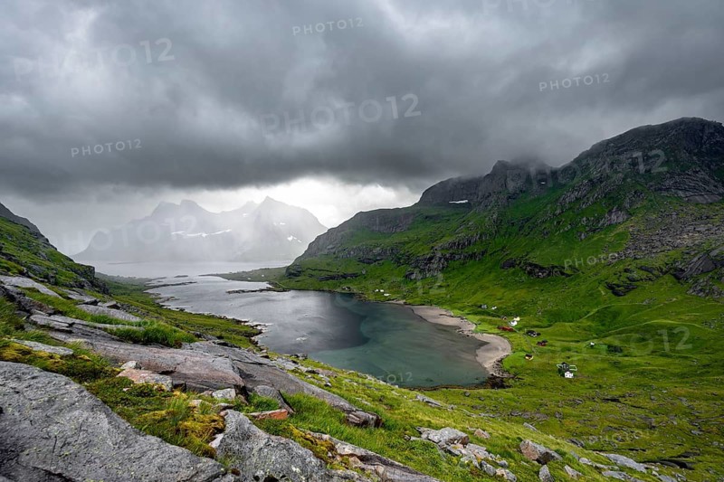 View over Bunesfjorden fjord, mountain peaks and dramatic clouds, climb to Helvetestinden summit, Lofoten, Norway