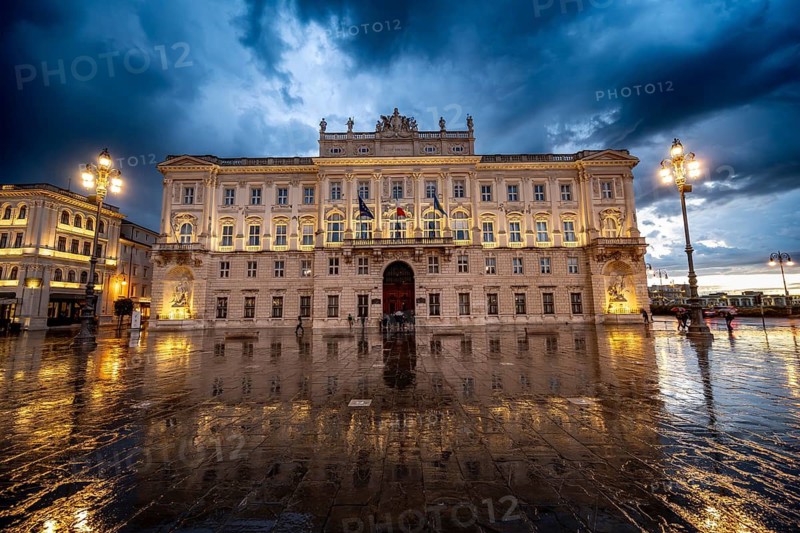 Illuminated square Piazza Unità d'Italia, Palazzo del Lloyd Triestino, with reflection, dramatic clouds, blue hour, old town, Trieste, Friuli-Venezia Giulia region, Italy