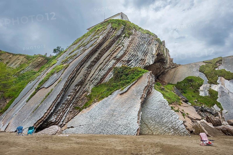 Empty chairs in front of distinctive rock cliffs as a geological formation made of rock layers, Flysch on Itzurun Beach in Zumaia, Spain