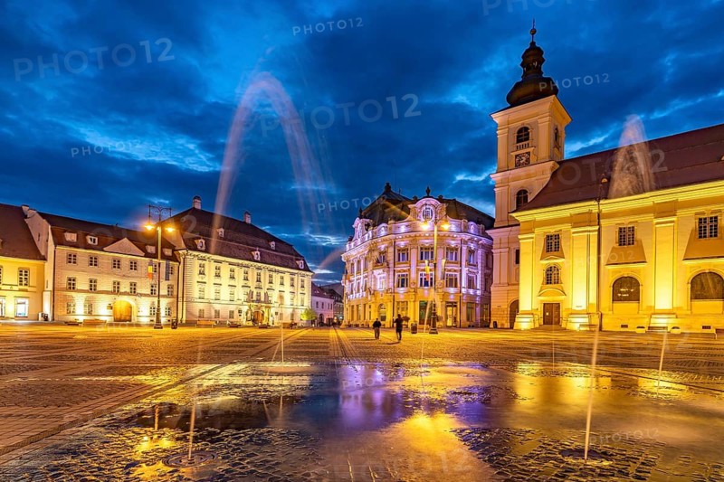 Fountain on Pia?a Mare Great Square, Brukenthal Museum, Sibiu City Hall and the Catholic Parish Church of the Holy Trinity at Dusk, Sibiu or Sibiu, Transylvania, Romania