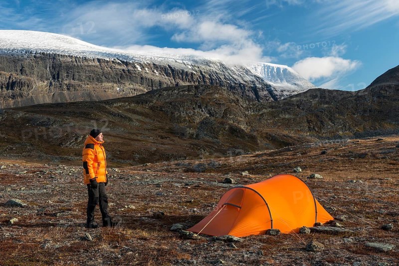 Man sitting next to tent with a view of Mount Sinnitjohkka, Kebnekaisefjäll, Norrbotten, Lapland, Sweden