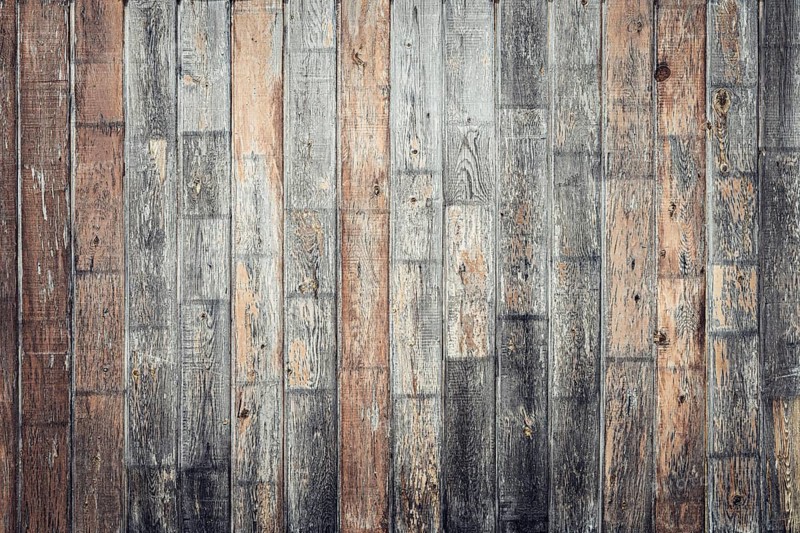 A textured wooden wall with varying shades of brown and gray. The planks are arranged horizontally, showcasing natural wood grain and imperfections