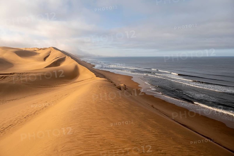 Sand dunes and sea with coastal fog in the morning, Atlantic coast and sandy desert with sea of dunes, Sandwich Harbour, Namib Naukluft Park, Namib Desert, Namibia