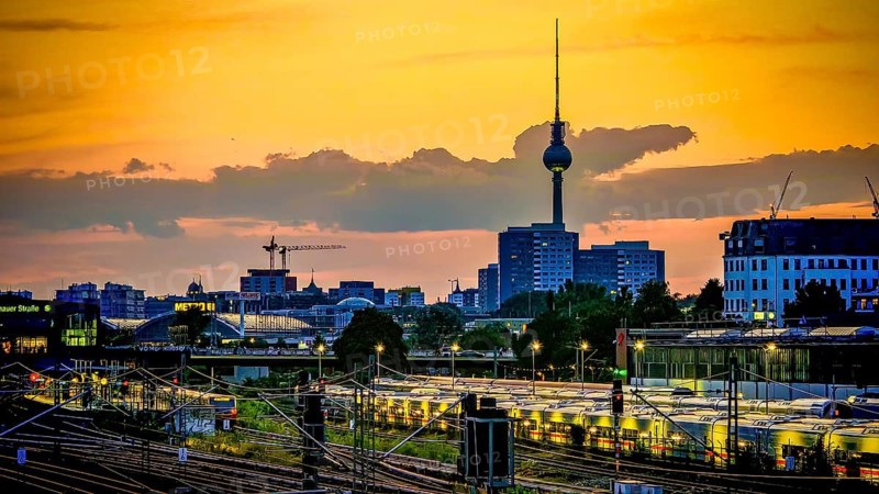 Sunset over train tracks and parked trains, Berlin with the distinctive television tower and urban skyline in the background, Berlin