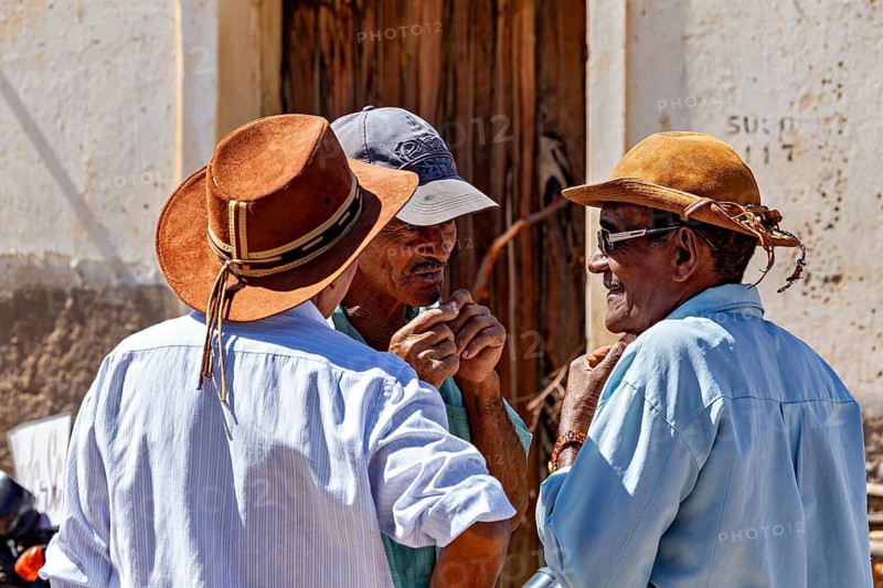 Three men wearing hats talking in a relaxed street scene in sunny weather, Three men talking in Campo Formoso in the Caatinga of Bahia in Brazil