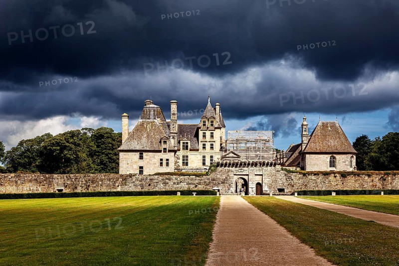 A castle in dramatic lighting with a sky surrounded by dark clouds, The Château de Kerjean Castle in Brittany