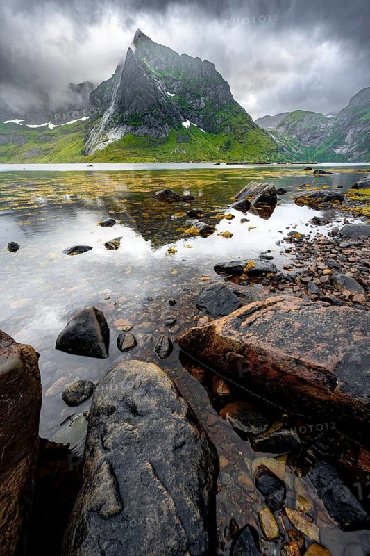 Shore with reflection, fjord landscape with mountains and dramatic clouds, Vindstad, Reinefjord, Lofoten, Norway