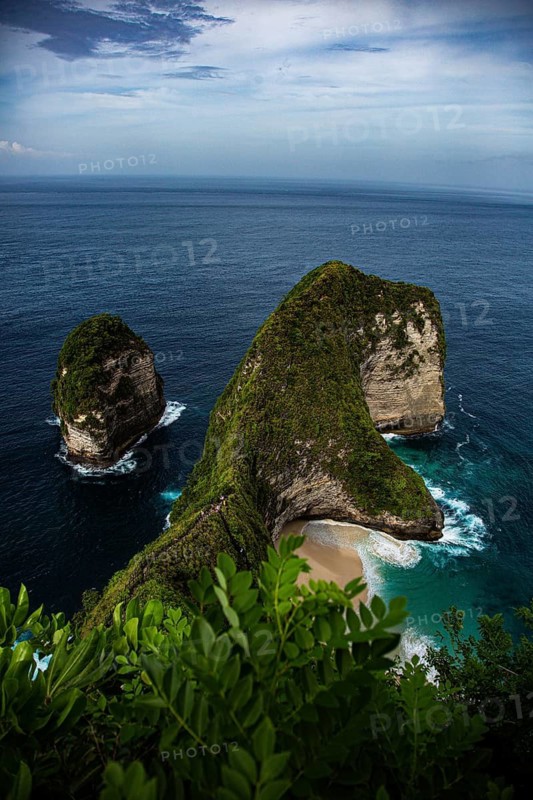 A spectacular cliff formation by the sea, with lush vegetation and calm waves, a view from above of the famous, deserted white sandy beach at Kelingking (T Rex Beach), Nusa Penida Island, Klungkung Regency, Bali, Indonesia, South-East Asia
