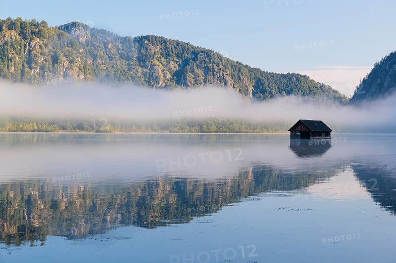 On an early autumn morning, a thin bank of fog hangs over the Almsee lake. Austria