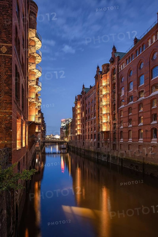 Historic brick warehouses are reflected in the calm water of the wall frame fleet of Hamburg's Speicherstadt at the Blue Hour, Hamburg, Germany