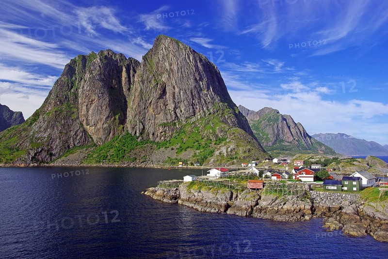 Dramatic mountains and coast with small village under blue sky and clouds, Hamnoey, Lofoten, Nordland, Norway
