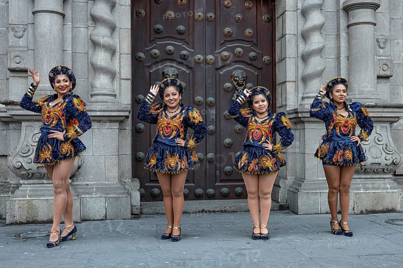 Street scene, colorfully dressed beautiful young woman posing in front of an entrance portal for a film shoot, Plaza des Armas, main square, Lima, Peru, South America
