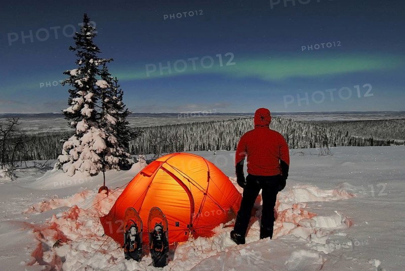 A man watches the Northern Lights (Aurora borealis) from his tent, Stubba Nature Reserve, Laponia World Heritage Site, Lapland, Norrbotten, Sweden, Scandinavia