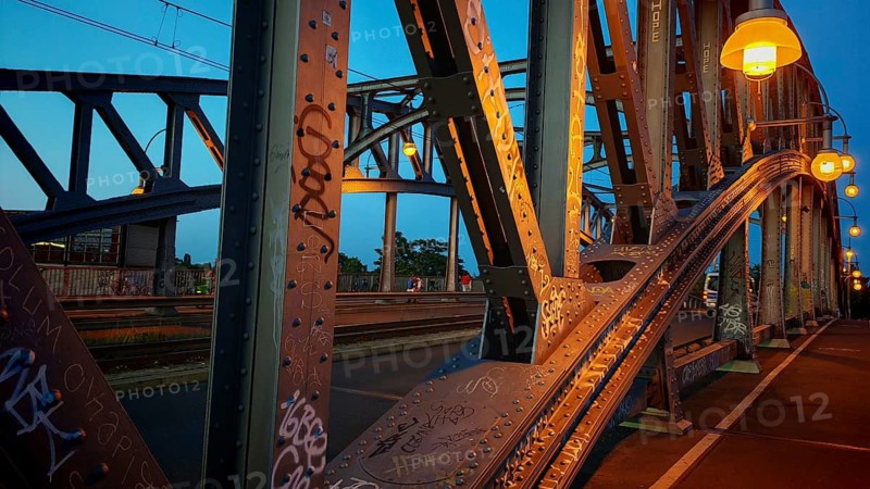 Steel bridge, with graffiti and lanterns in warm evening light, heritage-protected Bösebrücke, Bornholmer Straße, Berlin