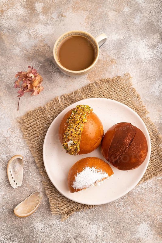 Maritozzo traditional Italian bun dessert, cup of coffee, on brown concrete background with linen textile, close up, top view, flat lay
