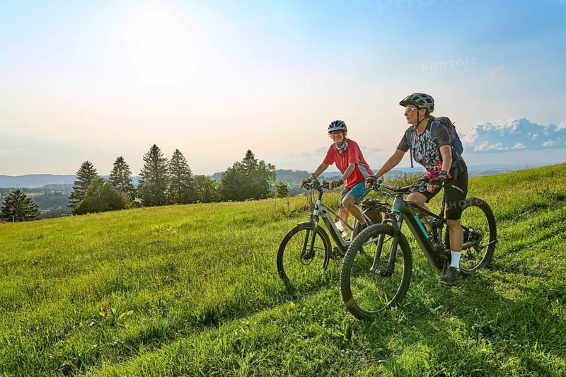 Two senior girlfriends have fun during a e-bike cycling tour in the Allgau Alps near Oberstaufen, Bavaria, Germany