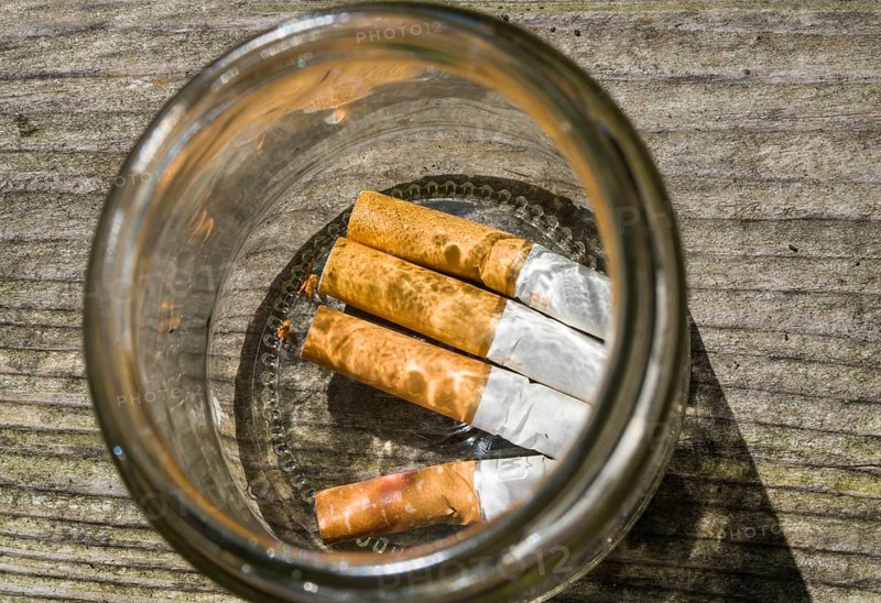 Cigarette butts in a glass ashtray