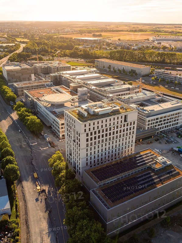Urban area with a distinctive tower and several industrial buildings in sunlight, construction site of the new airfield clinic, Böblingen, Germany