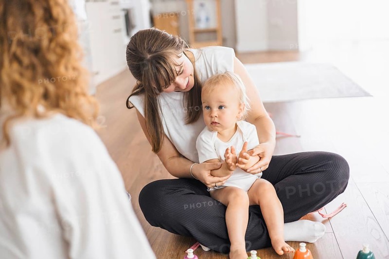 A relaxed setting with a woman attentively interacting with her baby on the floor