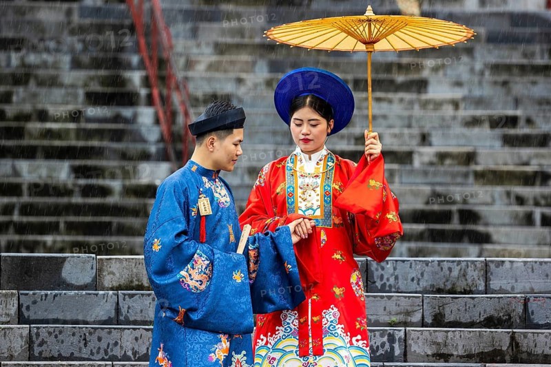 Traditional Vietnamese couple in colorful attire on stone steps at at Tu Doc Mausoleum, Hue, Vietnam