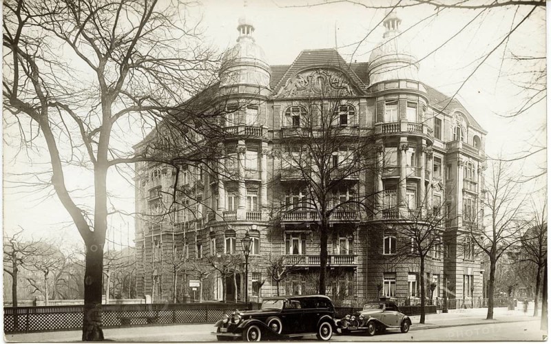Berlin, Charlottenburg, Dernburgplatz, Lietzensee, Kantstraße, Large building with rich art nouveau ornamentation next to two historic cars under trees