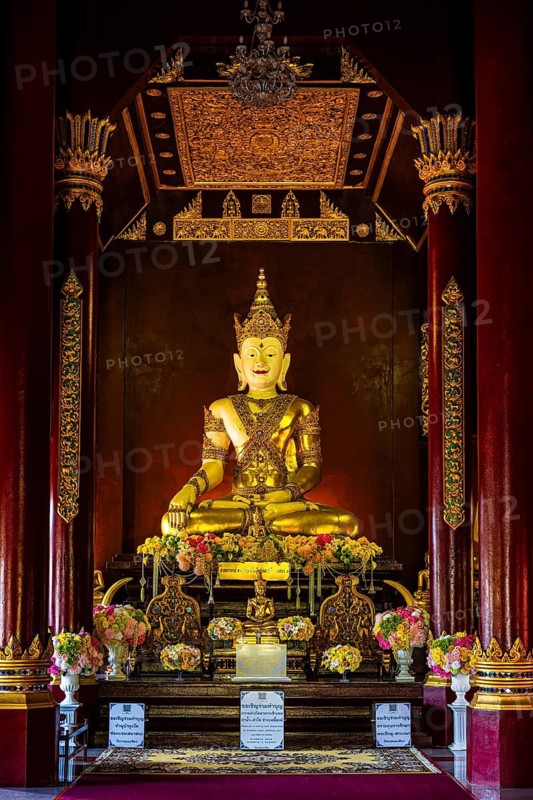 Gilded seated Buddha figure in the public prayer room of the Buddhist temple complex Wat Phra That Doi Kham, Chiang Mai, Thailand