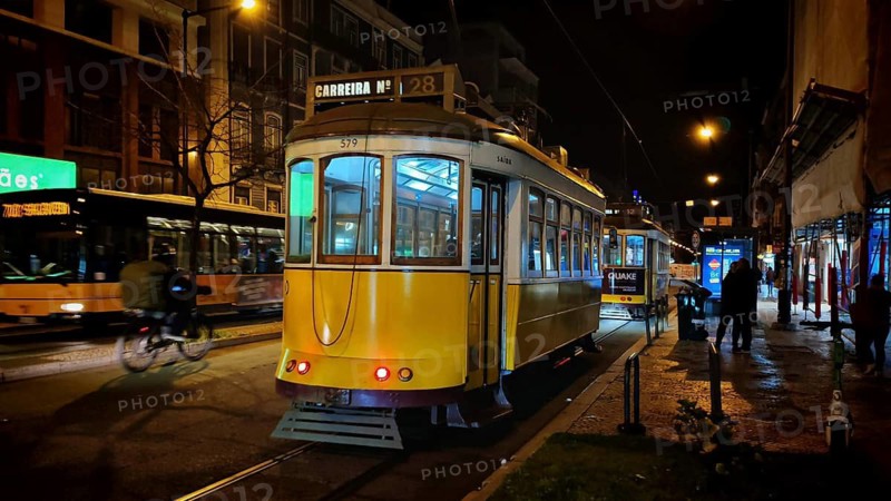 Two trams at night in front of city lights in the lively area of Lisbon, Lisbon, Portugal
