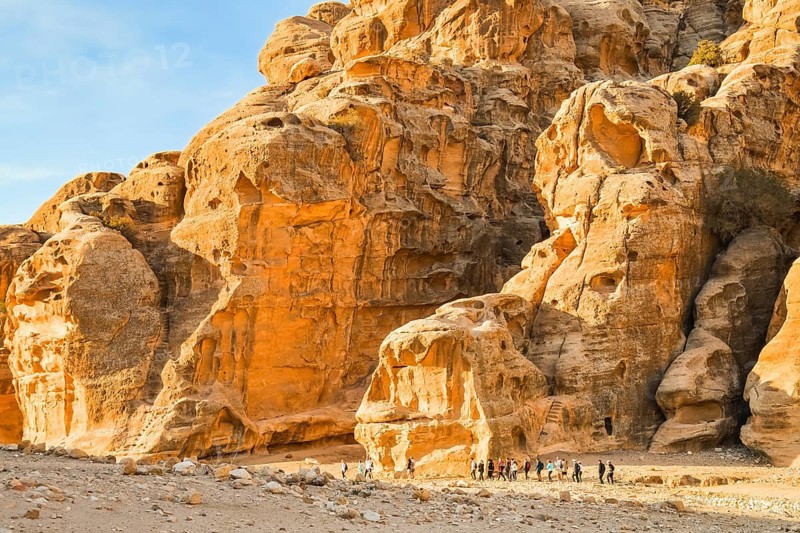 Hiking group on Back Door Trail from Little Petra to Petra walking through sandstone desert valley Jordan adventure tourism.Popular hiking moderate easy route