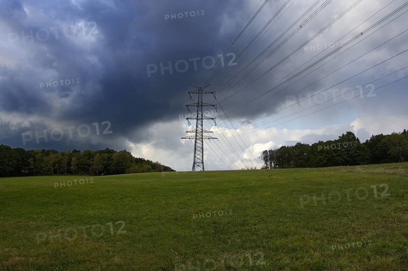High voltage pole in a meadow under a cloudy sky with dark clouds, Siegen, Meiswinkel